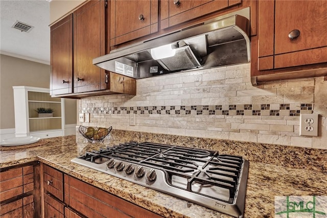 kitchen with tasteful backsplash, light stone countertops, ornamental molding, and stainless steel gas cooktop