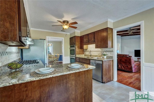 kitchen with sink, crown molding, ceiling fan, appliances with stainless steel finishes, and light stone countertops