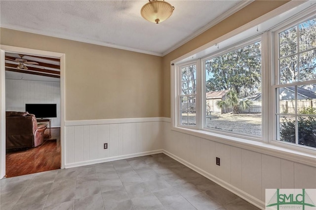 empty room with crown molding, ceiling fan, and a textured ceiling