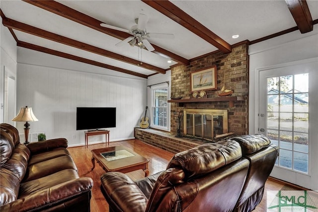 living room with beamed ceiling, plenty of natural light, light hardwood / wood-style floors, and a brick fireplace