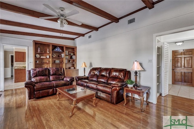 living room with hardwood / wood-style flooring, ceiling fan, built in features, and beamed ceiling