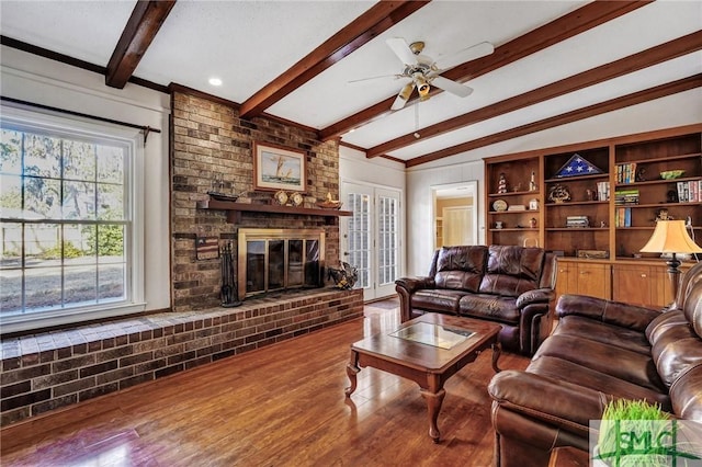 living room with ceiling fan, vaulted ceiling with beams, hardwood / wood-style floors, and a fireplace