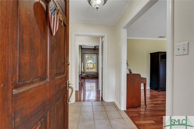 hallway with light tile patterned floors and crown molding