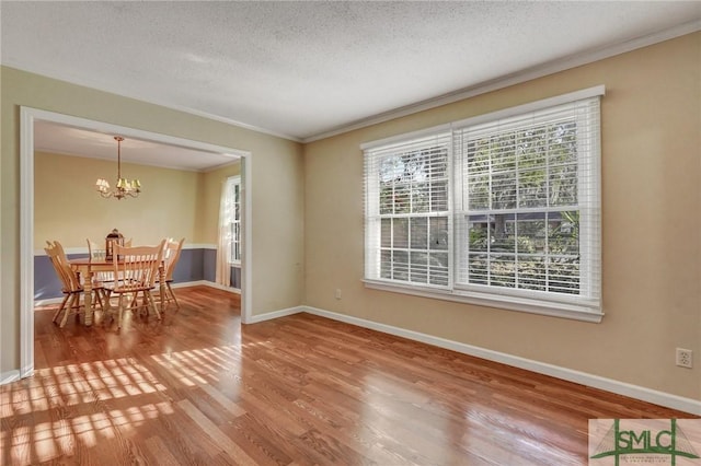 interior space featuring hardwood / wood-style flooring, ornamental molding, a textured ceiling, and a chandelier