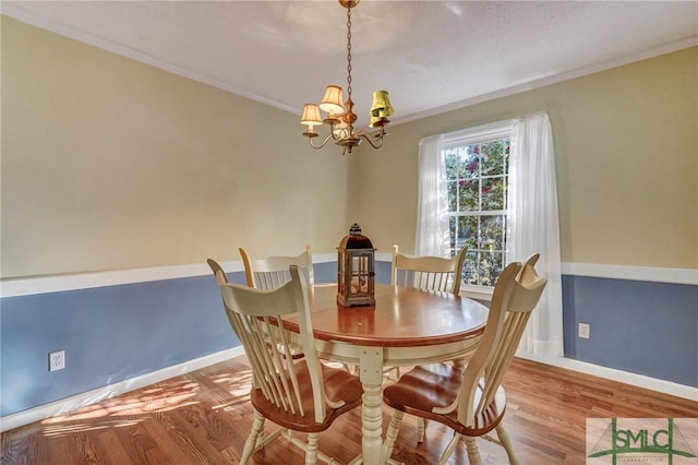 dining room featuring hardwood / wood-style flooring, ornamental molding, and a chandelier