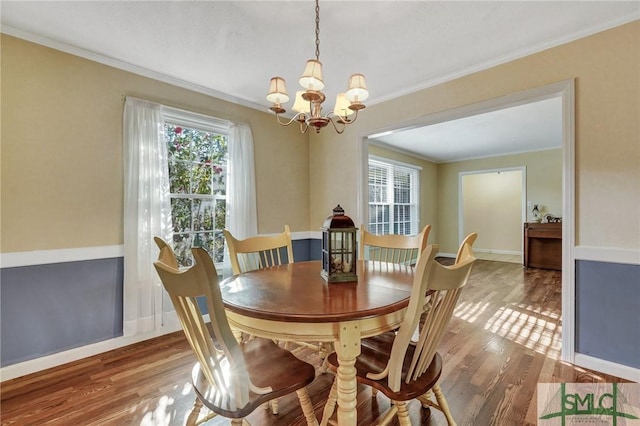 dining area featuring hardwood / wood-style flooring, ornamental molding, and a notable chandelier