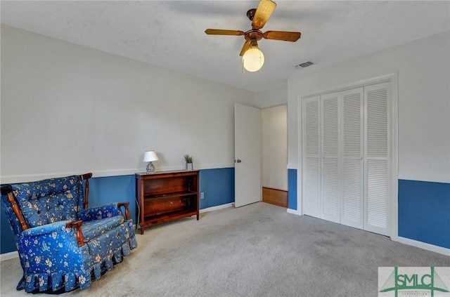 living area featuring carpet and ceiling fan