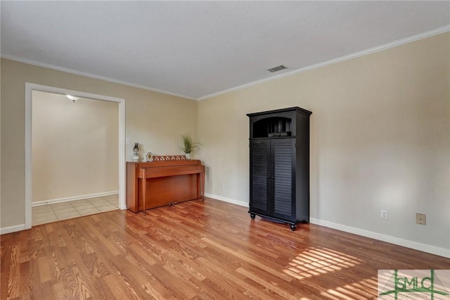 spare room featuring ornamental molding and light wood-type flooring