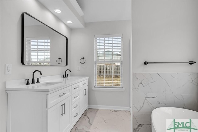 bathroom with vanity, a tub, and tile walls