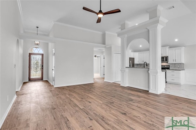 unfurnished living room featuring crown molding, sink, ceiling fan with notable chandelier, and light hardwood / wood-style flooring