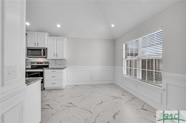 kitchen featuring lofted ceiling, white cabinetry, stone countertops, stainless steel appliances, and backsplash