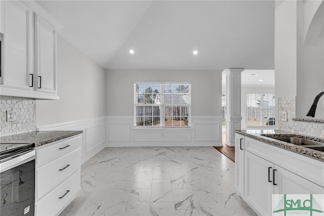 kitchen featuring sink, plenty of natural light, decorative columns, white cabinets, and stainless steel range with electric cooktop