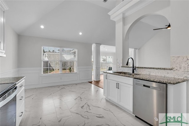 kitchen featuring appliances with stainless steel finishes, decorative columns, white cabinetry, sink, and dark stone counters