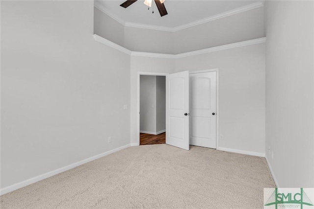 spare room featuring carpet floors, ornamental molding, ceiling fan, and a high ceiling