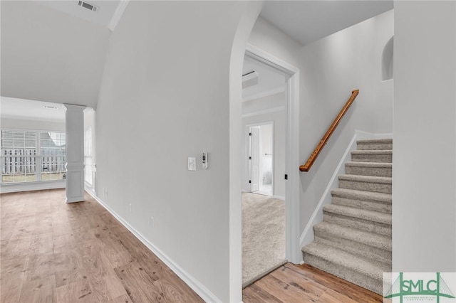 stairway with hardwood / wood-style floors, ornamental molding, and decorative columns