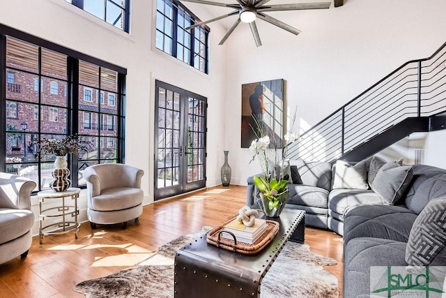 living room featuring wood-type flooring, a towering ceiling, and french doors