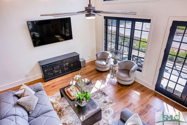 living room featuring ceiling fan, wood-type flooring, and a wealth of natural light