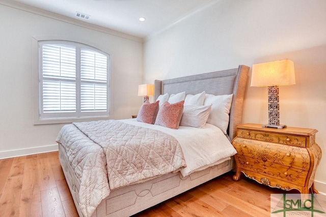 bedroom featuring ornamental molding and light hardwood / wood-style flooring