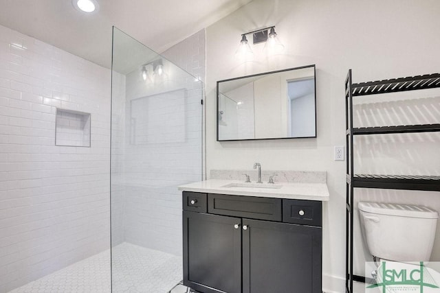 bathroom with vanity, tiled shower, and toilet