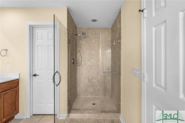 bathroom with tiled shower, vanity, and tile patterned flooring