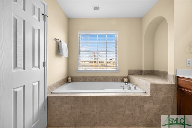 bathroom featuring vanity and a relaxing tiled tub