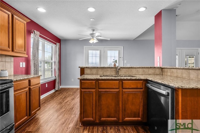 kitchen with stainless steel appliances, dark hardwood / wood-style flooring, light stone countertops, and sink