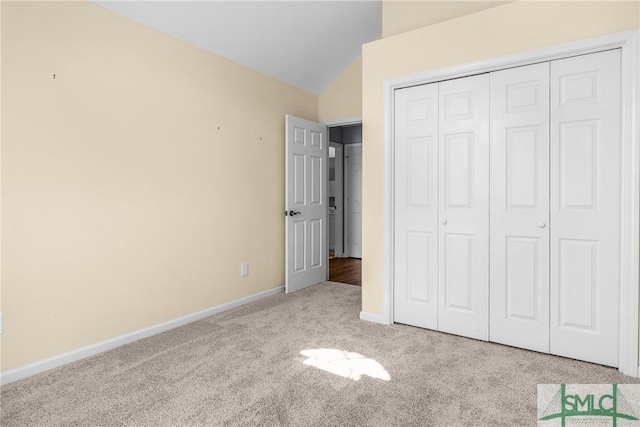 unfurnished bedroom featuring light carpet, lofted ceiling, and a closet