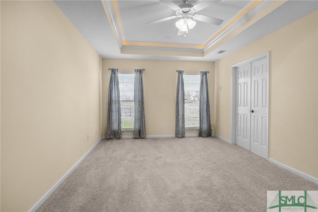 carpeted spare room with crown molding, ceiling fan, and a raised ceiling