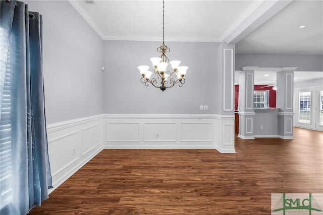 unfurnished dining area with ornate columns, crown molding, dark wood-type flooring, and ceiling fan with notable chandelier