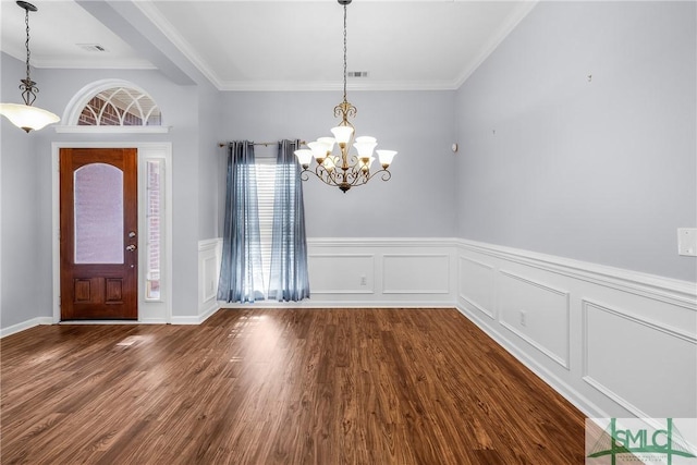 foyer featuring dark hardwood / wood-style flooring, ornamental molding, and an inviting chandelier