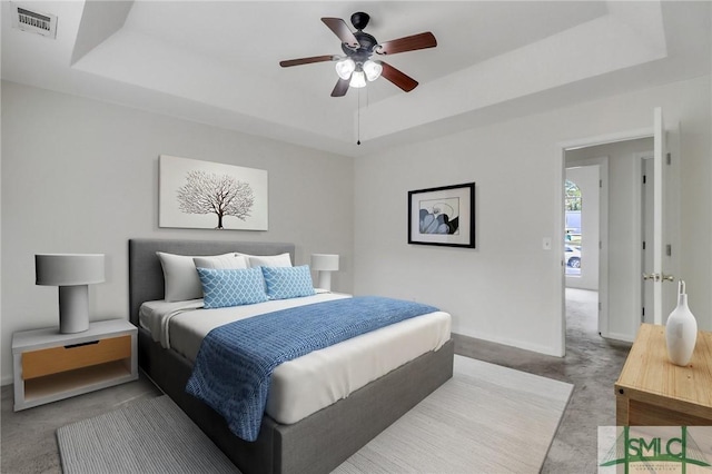 bedroom with carpet flooring, ceiling fan, and a tray ceiling