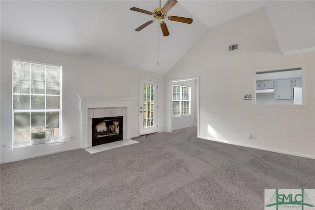 unfurnished living room featuring a tile fireplace, light colored carpet, ceiling fan, and high vaulted ceiling