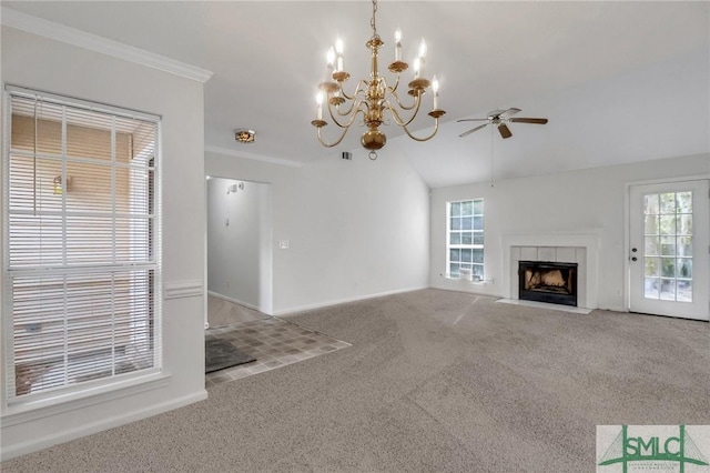 unfurnished living room featuring ceiling fan with notable chandelier, a tile fireplace, a healthy amount of sunlight, and carpet