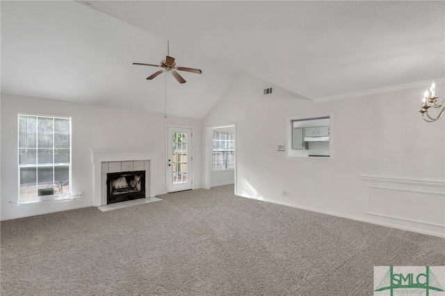 unfurnished living room featuring a tiled fireplace, ceiling fan with notable chandelier, vaulted ceiling, and carpet