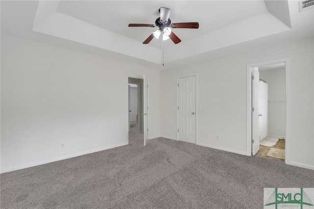 unfurnished bedroom featuring ceiling fan, light colored carpet, and a tray ceiling