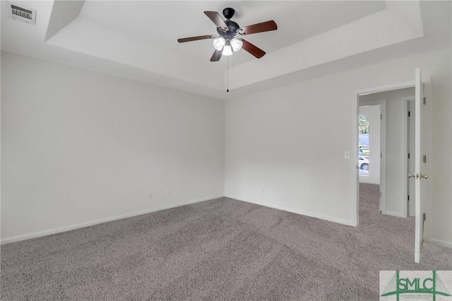 carpeted empty room with a tray ceiling and ceiling fan