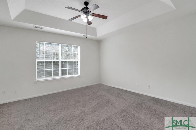 spare room featuring ceiling fan, a raised ceiling, and carpet floors