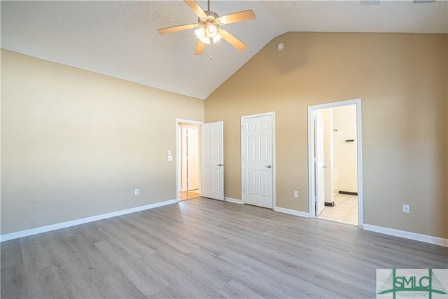 unfurnished bedroom with high vaulted ceiling, light hardwood / wood-style floors, ceiling fan, and ensuite bathroom