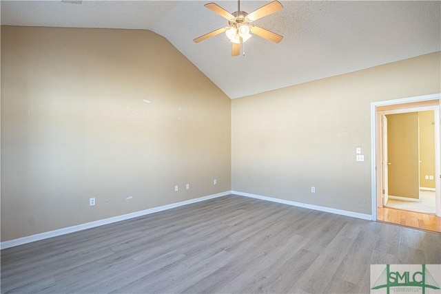 empty room with ceiling fan, lofted ceiling, a textured ceiling, and light wood-type flooring