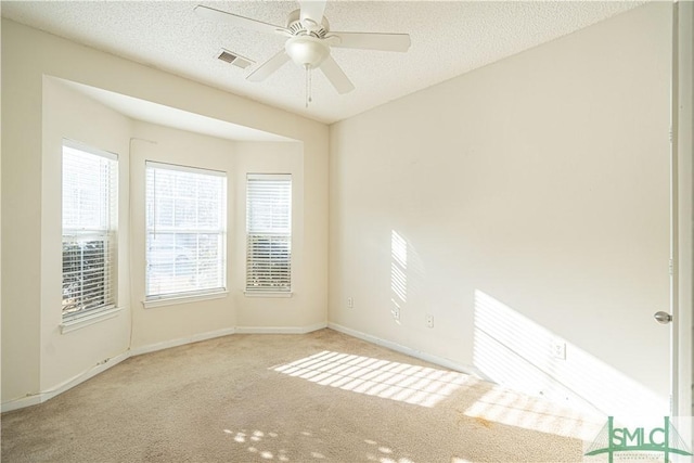 unfurnished room featuring ceiling fan, light colored carpet, and a textured ceiling