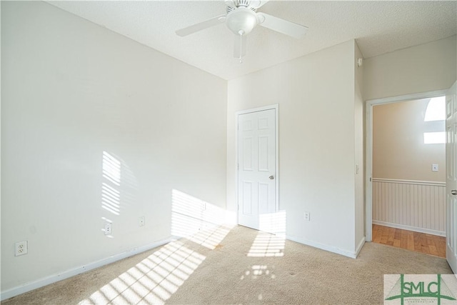 empty room with ceiling fan, light colored carpet, and a textured ceiling