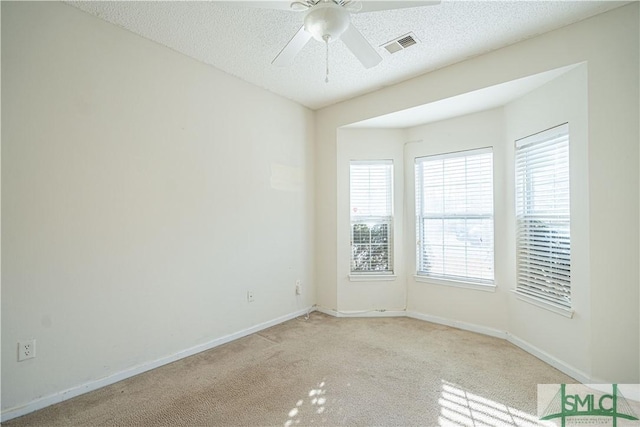 carpeted spare room featuring ceiling fan and a textured ceiling