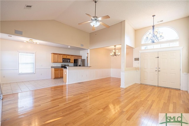 foyer featuring high vaulted ceiling, ceiling fan with notable chandelier, a textured ceiling, and light wood-type flooring