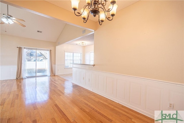 unfurnished dining area with light hardwood / wood-style flooring, ceiling fan with notable chandelier, and vaulted ceiling