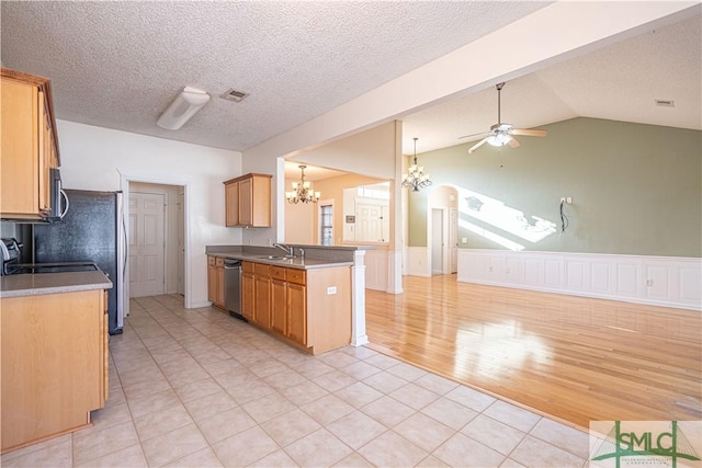 kitchen with sink, appliances with stainless steel finishes, ceiling fan with notable chandelier, vaulted ceiling, and kitchen peninsula