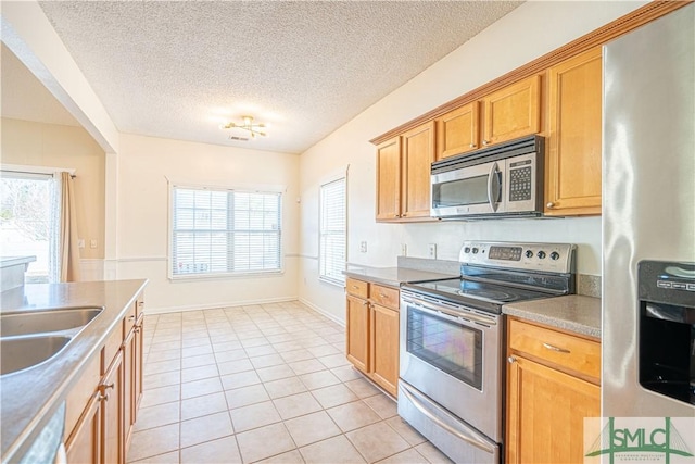 kitchen featuring sink, a wealth of natural light, light tile patterned flooring, and appliances with stainless steel finishes