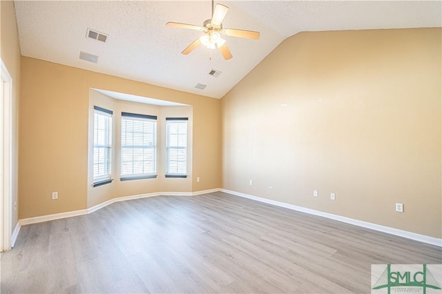 spare room with vaulted ceiling, ceiling fan, a textured ceiling, and light hardwood / wood-style flooring