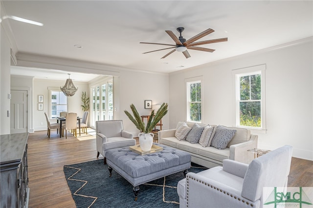 living area featuring a ceiling fan, baseboards, ornamental molding, and dark wood-type flooring