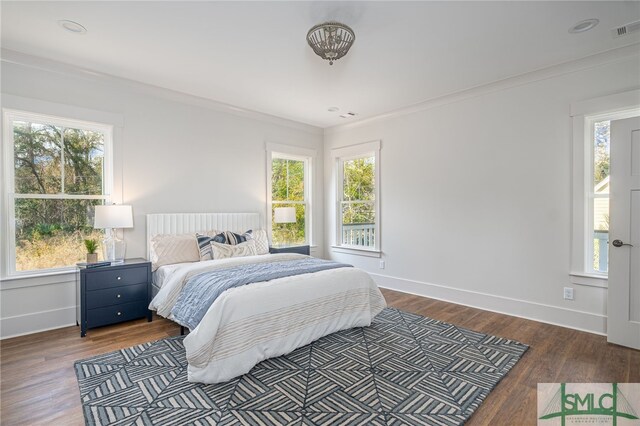 bedroom with visible vents, multiple windows, baseboards, and wood finished floors