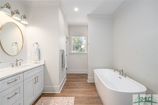 bathroom featuring recessed lighting, vanity, wood finished floors, a freestanding tub, and baseboards